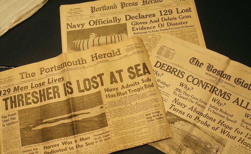 Yellowed newspaper front pages from 1963 announce the loss of the USS Thresher.