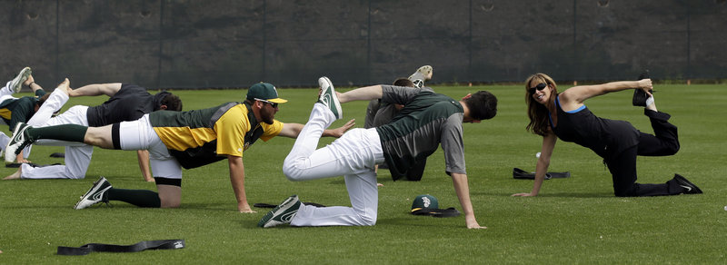 The Athletics, who have learned to stretch their payroll, perform yoga stretches with the help of instructor Katherine Roberts before Wednesday’s exhibition game against Colorado in Phoenix.