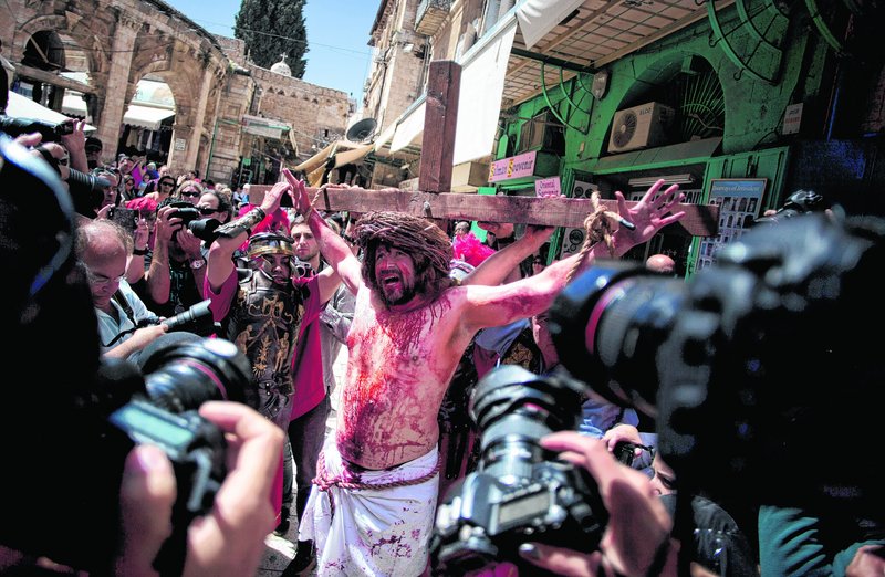 A Christian pilgrim dressed as Jesus Christ is attached to a cross during a reenactment of the crucifixion during a Good Friday procession in Jerusalem on Friday. Israel said it expects some 150,000 visitors during Easter week and the Jewish festival of Passover, which coincide this year.