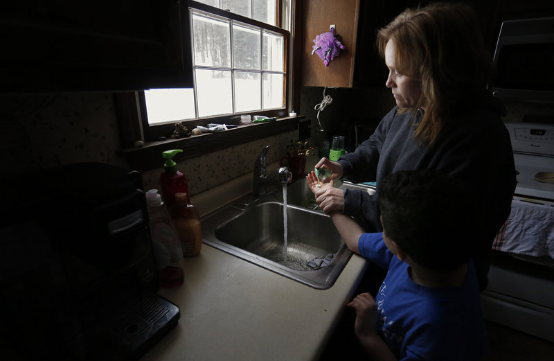 Marie Beaulieu of Jay helps her son Shavar, 8, wash his hands. She and her family adopted him after taking him in as a foster child. Lawmakers have backed spending cuts that affect support services for foster care adoptive parents like the Beaulieus, while regulators have failed to track long-term trends in foster care.