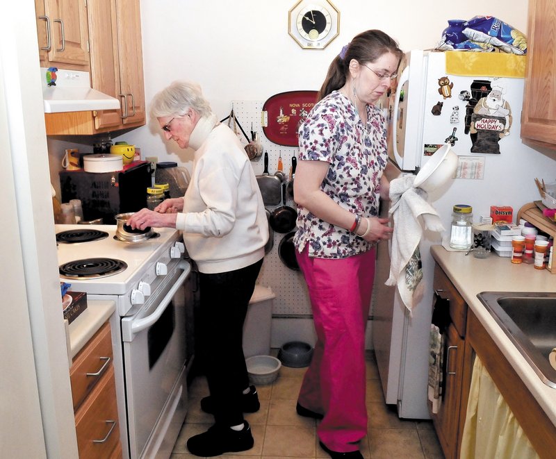Waterville resident Marie Rouleau, 84, left, and Zandra Luce, a personal support specialist, work in the kitchen preparing a meal. Rouleau is on a waiting list for Meals on Wheels.