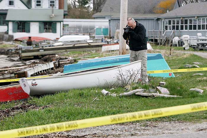 Cumberland County Sheriff's Department Detective Keith Cook photographs a boat near Cook's Lobster House on Bailey Island Thursday as they investigate the discovery of a body along the shore.