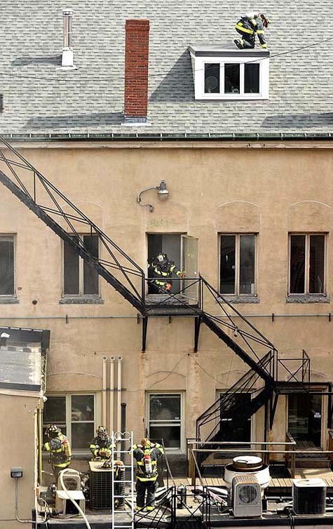 Firefighters check the windows and doors in the back of The Grill Room on Exchange Street Monday.