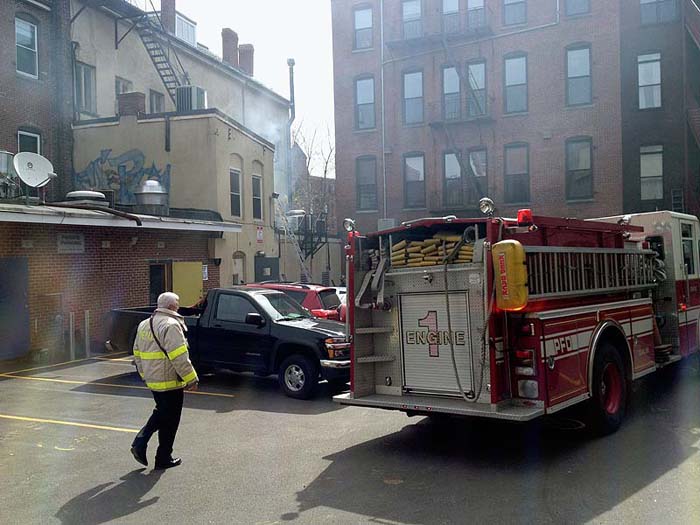Firefighters investigate a fire in a building at 86 Exchange St. in Portland on Monday.