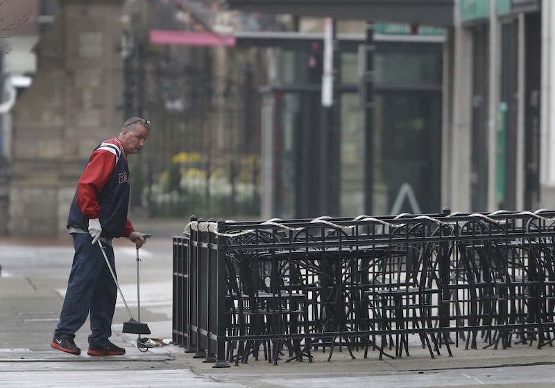 A man sweeps around the outdoor seating area at a business on Boylston Street in Boston Tuesday, April 23, 2013 about two blocks from the Boston Marathon finish line where two bombings killed three people and injured many. Boylston Street businesses near the finish area remain closed to the public, but business owners are slowly being allowed to prepare to re-open. (AP Photo/Elise Amendola)