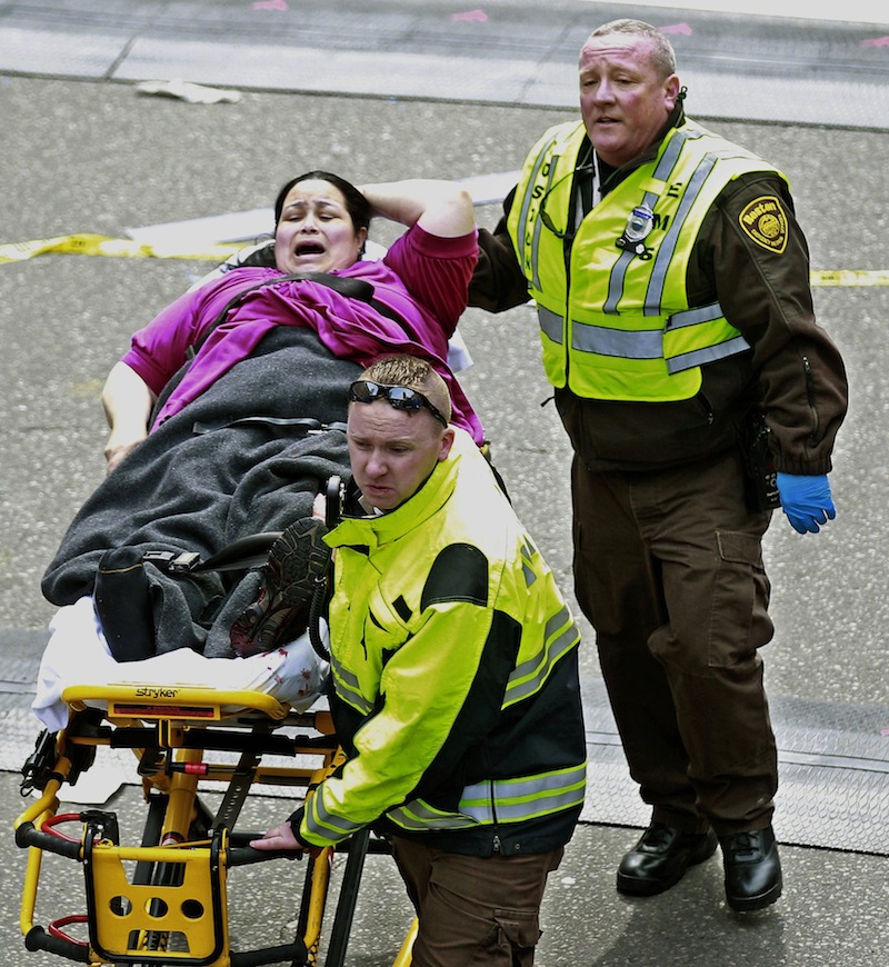 Medical workers aid an injured woman at the finish line of the 2013 Boston Marathon following two explosions there, Monday, April 15, 2013 in Boston. Two bombs exploded near the finish of the Boston Marathon on Monday, killing at least two people, injuring at least 23 others and sending authorities rushing to aid wounded spectators. (AP Photo/Charles Krupa)
