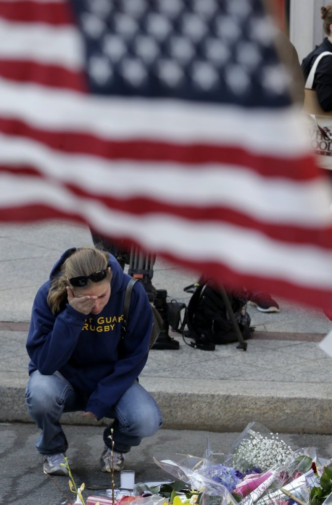 Jillian Blenis, 30, of Boston, reacts while stopping at a makeshift memorial, Wednesday, April 17, 2013, in Boston. The city continues to cope following Monday's explosions near the finish line of the Boston Marathon. (AP Photo/Julio Cortez)