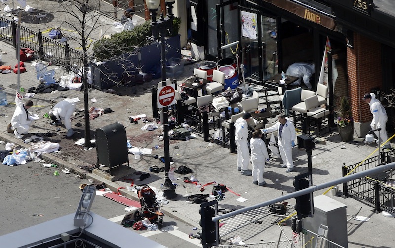 Investigators in haz-mat suits examine the scene of the second bombing on Boylston Street in Boston Tuesday, April 16, 2013 near the finish line of the 2013 Boston Marathon, a day after two blasts killed three and injured over 170 people. (AP Photo/Elise Amendola)