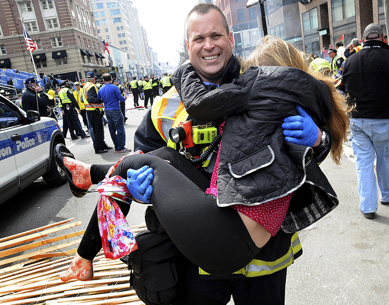 Boston Firefighter James Plourde carries an injured girl away from the scene after a bombing near the finish line of the Boston Marathon on Monday. Doctors say the actions of first-responders saved lives and limbs.