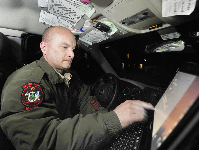 Marine patrol officer Tom Hale uses his computer to check license plate numbers as he keeps tabs on fishermen.