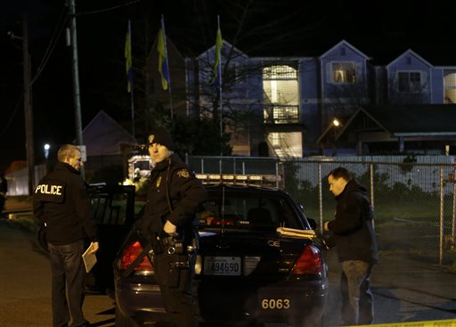 Police officers stand by their car on Monday morning at the scene of an overnight shooting that left five people dead at the Pinewood Village apartment complex in Federal Way, Wash.