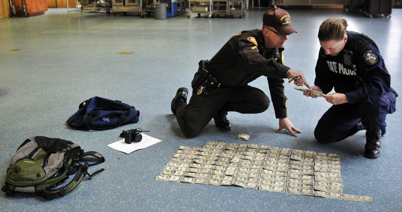 Staff photo by Andy Molloy Somerset County Sheriff's Office Cpl. Gene Cole, left, helps Maine State Police Trooper Diane Vance inventory money recovered from Christopher Knight Tuesday April 9, 2013 at the Pine Tree Camp in Rome. Knight, a hermit who lived in the woods since April 1986, was apprehended when he broke into the camp, police claim. He was captured carrying a knapsack and bag of tools. Many of bills date from the 1980s and 1990s, Vance said, and were never circulated by Knight.