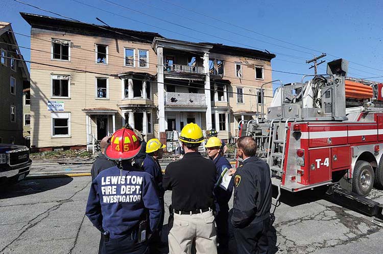 Lewiston fire officials and state fire marshals begin to investigate the scene of a fire that destroyed three apartment buildings in Lewiston on Monday.