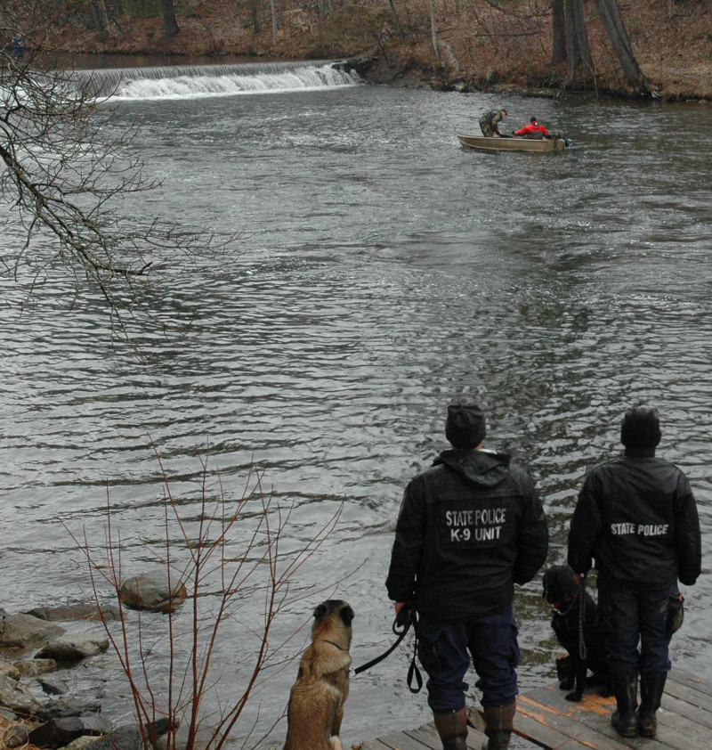State police use a boat to recover the body of Romeo Parent, 20, from Jug Stream in East Monmouth on Friday. In the foreground are the state police dogs who discovered the body, and their handlers.