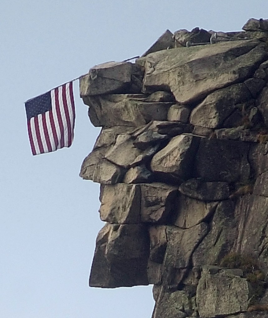 An American flag hangs over the brow of the Old Man of the Mountain in Franconia, N.H., on Oct. 2, 2001.