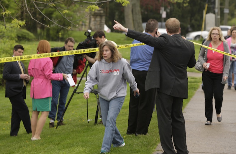 Parents and other family members cross under a police line to check on their children, Monday, April 29, 2013, at LaSalle High School in Cincinnati, where a high school student pulled out a gun and shot himself in a classroom on Monday. The Hamilton County sheriff's office says the youth was taken to a hospital with a self-inflicted wound. They say there apparently was no threat to other students at the private school. (AP Photo/Cincinnati Enquirer, Glenn Hartong)