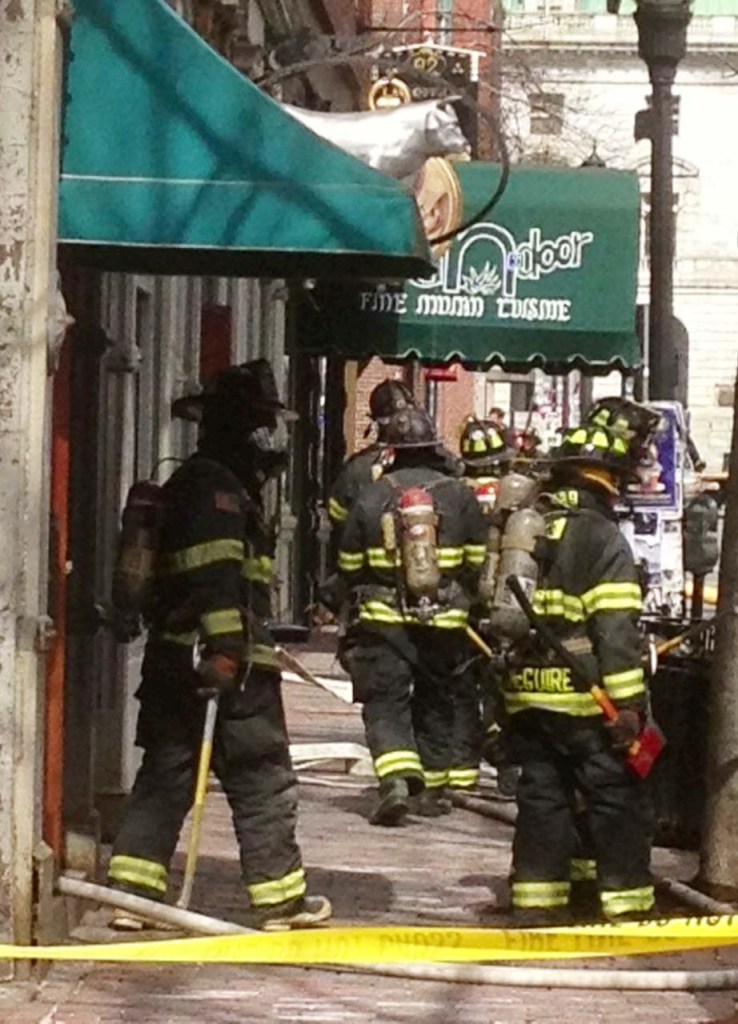 Firefighters leave the building at 86 Exchange St. in Portland where a fire broke out on Monday morning.