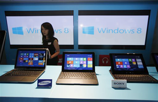 A woman walks past laptop computers running Microsoft Windows 8 operating system during the software's launching ceremony in Hong Kong in October 2012.