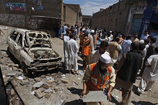 People gather at the site of an explosion outside an election office of a candidate in Peshawar, Pakistan, Sunday.