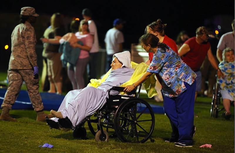 Emergency workers assist an elderly person at a staging area at a local school stadium Wednesday in West, Texas, following an explosion at a fertilizer plant near Waco.