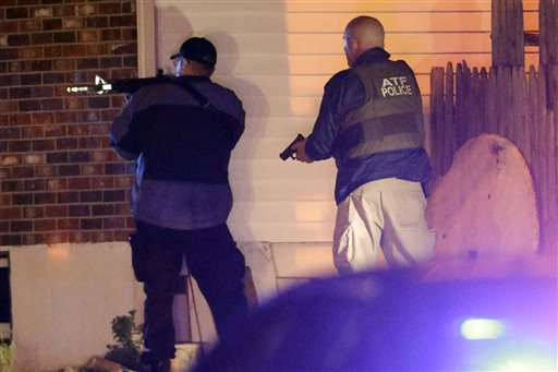 Police officers aim their weapons Friday in Watertown, Mass., where residents of the Boston suburb have been advised to keep their doors locked and not let anyone in.