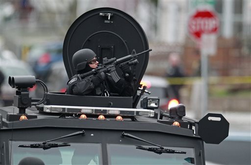 Police in tactical gear and riding in an armored police vehicle surround an apartment building in Watertown, Mass., on Friday as they hunt for the surviving suspect in the Boston marathon bombings.