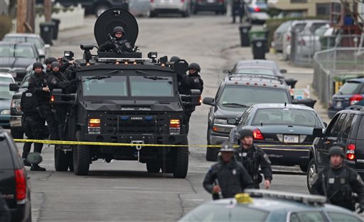 Police in tactical gear arrive on an armored police vehicle as they surround an apartment building while looking for a suspect in the Boston Marathon bombings in Watertown, Mass., on Friday.