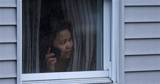 A woman looks out a window at her home as police start to search an apartment building while looking for a suspect in the Boston Marathon bombings in Watertown, Mass., on Friday.