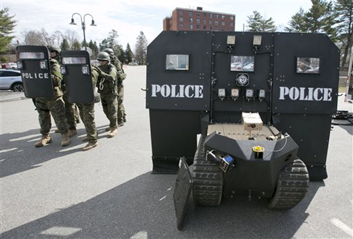 A team of police line up behind hand-held bulletproof shields, showing the relative lack of protection compared to a SWAT robot, right, during a demonstration for the media in Sanford on Thursday.