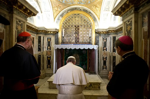 In this picture made available by the Vatican newspaper L'Osservatore Romano, Pope Francis, flanked by Cardinal Angelo Comastri, left, and Bishop Vittorio Lanzani, kneels in front of what is believed to be the burial site of St. Peter.