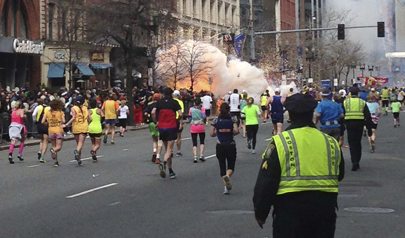 In this Reuters photo from Monday, runners continue to run towards the finish line of the Boston Marathon as an explosion erupts near the finish line. A congressman says investigators still don't know whether the Boston Marathon bombs were the work of domestic or foreign attackers. (REUTERS/Dan Lampariello)
