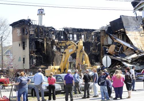 Spectators watch demolition efforts Tuesday at the scene of the fire that heavily damaged three apartment buildings Monday in Lewiston.