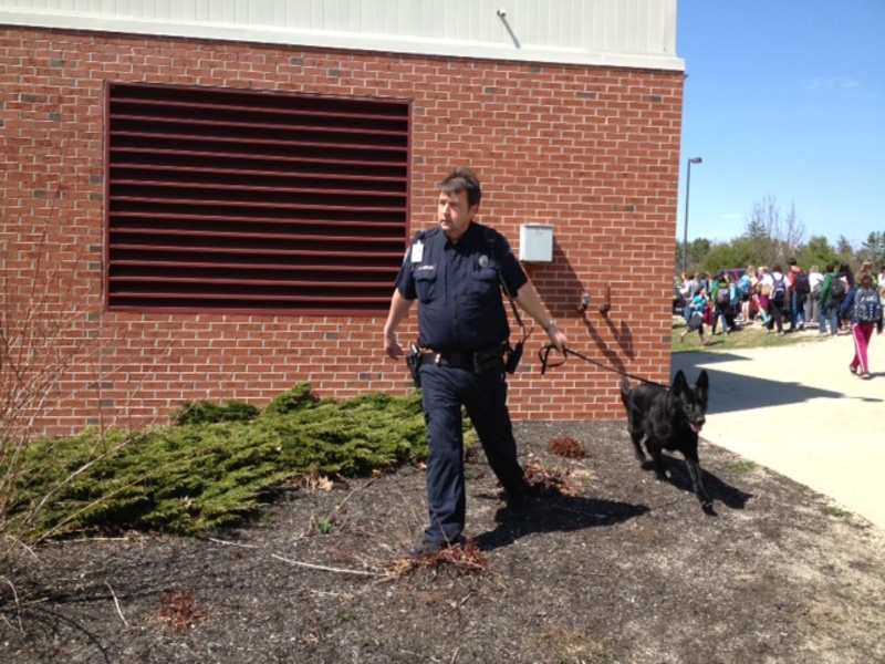 A Portland police officer and his bomb-sniffing dog assist the Gorham Police Department in investigating a bomb threat at Gorham Middle School on Friday.