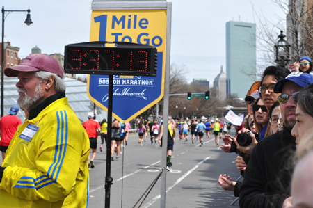 Onlookers watch as runners cross the “1 Mile To Go” marker shortly after 12 p.m. Monday at the Boston Marathon. Just before 3 p.m., two bombs exploded 12 seconds apart at the marathon finish line, killing three and injuring 176 others.