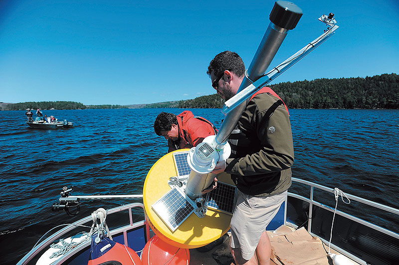 Colby College chemistry professor Whitney King, at rear, and Colby College senior Matt LaPine, 22, install a research buoy named Goldie in Great Pond in Belgrade.