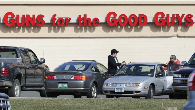 Shoppers leave Hoffman’s Gun Center on Tuesday in Newington, Conn. Customers are packing gun stores in the state after the unveiling of new gun-control legislation.