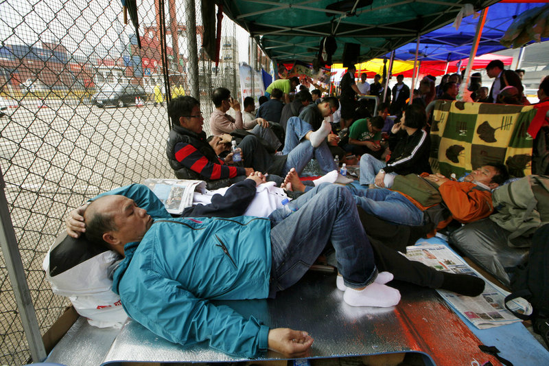 Several hundred dock workers and their supporters camp out Wednesday on the road in front of a container terminal on the seventh day of their strike in Hong Kong.