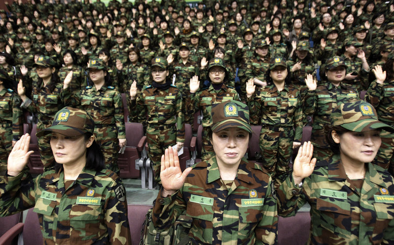 South Korean army reservists raise their hands to adopt a resolution against North Korea during a rehearsal for their Foundation Day ceremony at a gymnasium in Seoul on Friday. About 1,000 reservists denounced North Korea for its escalating threats of war.
