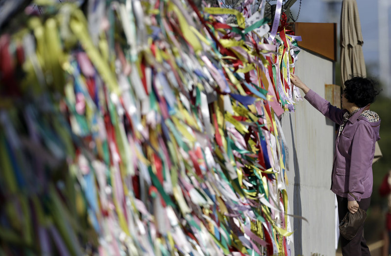 A woman reads messages on ribbons Sunday left by visitors to the Imjingak Pavilion near the border village of Panmunjom, South Korea, expressing their wishes for the reunification of the two Koreas. North Korea last week suggested diplomats leave the country.