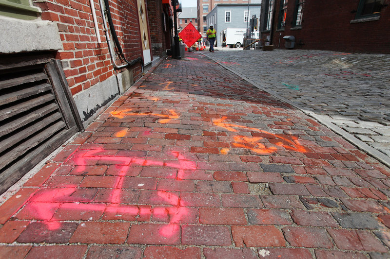 Spray paint marks where utility lines are located under Wharf Street and its sidewalks as Unitil replaces cast-iron natural gas lines in the Old Port with new plastic lines.