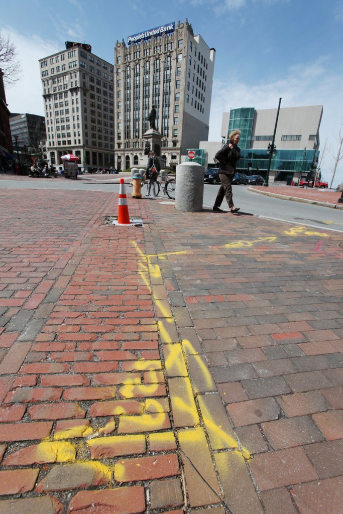 Yellow spray paint marks the underground locations of natural gas lines near Monument Square in Portland. The markings are required before digging projects so contractors can avoid rupturing lines.