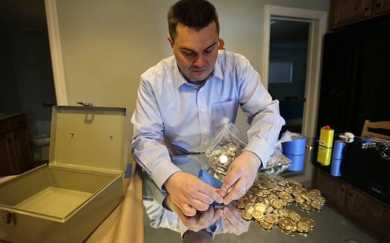 Mike Caldwell, a 35-year-old software engineer, looks over bitcoin tokens at his shop in Sandy, Utah. Caldwell mints physical versions of bitcoins, cranking out homemade tokens with codes protected by tamper-proof holographic seals.