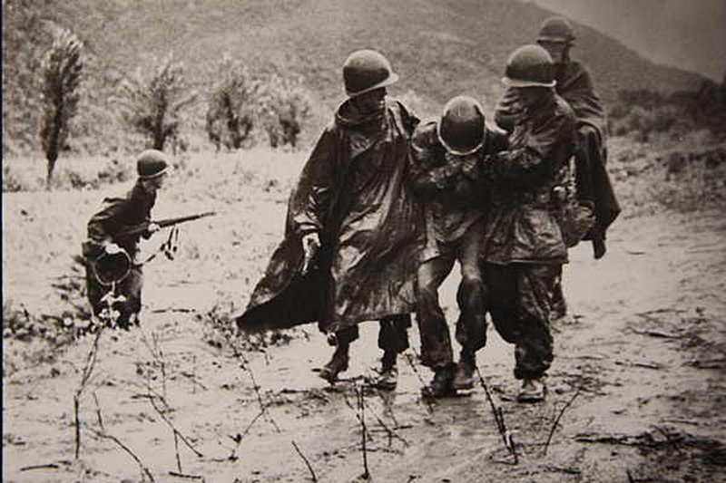 Image provided by the Army shows chaplain Capt. Emil J. Kapaun, right, and Capt. Jerome A. Dolan, a medical officer with the 8th Cavalry Regiment, carrying an exhausted soldier off a battlefield during the Korean War in November 1950.