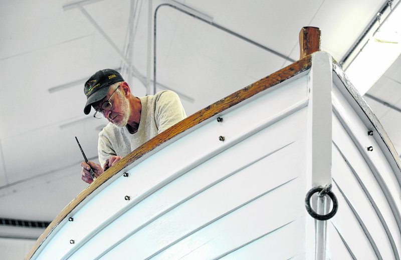 Volunteer Don St. Pierre paints a former Coast Guard motorized surfboat on March 28 that is being restored at Coast Guard Station Chatham in Massachusetts.