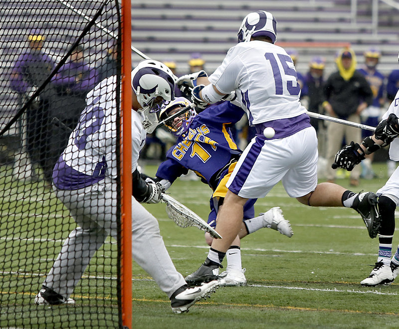 James Doyle of Deering knocks down Hilmar Smith of Cheverus as Deering goalie Riley Archer concentrates on the ball Friday during Cheverus’12-6 victory in a season-opening SMAA boys’ lacrosse game at Deering High. Cheverus is the defending Eastern Class A champion.