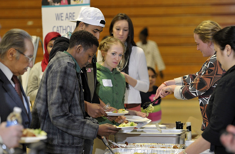 Maggie Mullin, right, puts salad on the plate of Emily Keef of New Gloucester, another volunteer, as lunch is served during New Mainers Day on the University of Southern Maine’s campus in Portland on Saturday.
