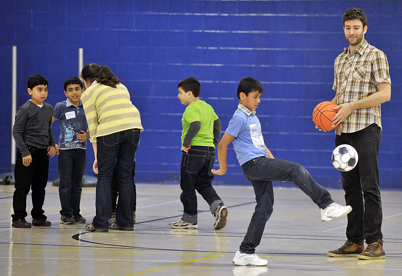 Jake Acker watches as Omar Jashaami shows off his soccer skills, while another volunteer works with a group of children during New Mainers’ Day at the Sullivan Recreation and Fitness Complex on the University of Southern Maine’s campus in Portland on Saturday.
