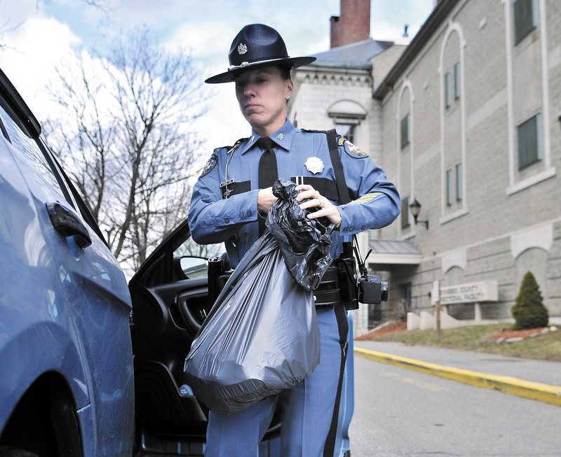 Maine State Police Trooper Diane Perkins-Vance carries a bag of Christopher Knight’s clothing Sunday at the Kennebec County jail, where she filed new charges against him.