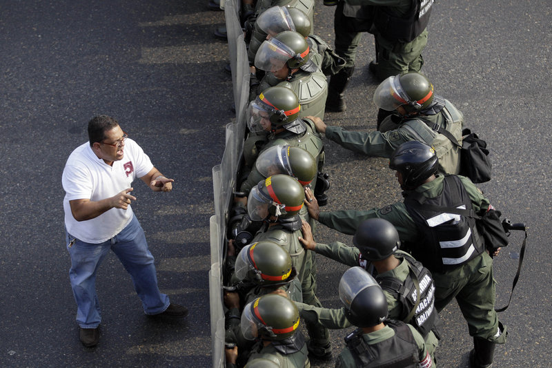 A man confronts riot police along a highway in Caracas, Venezuela, on Monday. Troops fired tear gas and plastic bullets to disperse students protesting presidential election results.