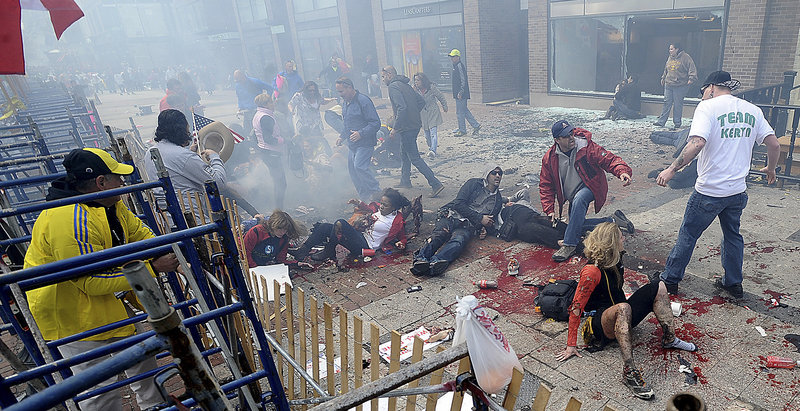 Injured people and debris lie on the sidewalk near the Boston Marathon finish line following an explosion in Boston, Monday, April 15, 2013. (AP Photo/MetroWest Daily News, Ken McGagh)